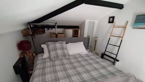 Una camera da letto con un letto, un armadio, una lampada rossa, una scala e un quadro appeso al muro.