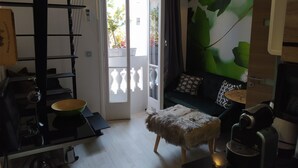 Un soggiorno moderno con un divano, un tavolino da caffè, un piccolo tavolo con un bollitore e un quadro appeso al muro.