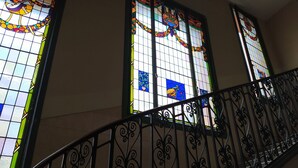 Una scala con ringhiere in ferro battuto nero decorate e finestre con vetrate colorate.