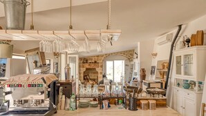 A rustic kitchen with a coffee machine, hanging wine glasses, and various kitchen utensils. - Villa 'Camera 2' with Sea View, Private Pool and Wi-Fi (Lido Marini)
