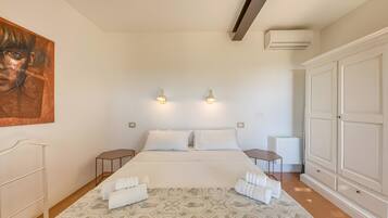 A bedroom with a bed, bedside tables, a wardrobe, and a painting on the wall.