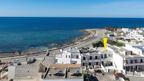 Un pueblo costero con edificios blancos, una playa y un cielo azul despejado.