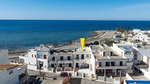 Un pueblo costero con edificios blancos, una playa y un cielo azul despejado.