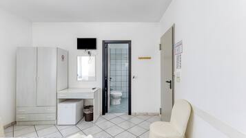 A bedroom with a bed, a desk, a wardrobe, a toilet, and a chair.