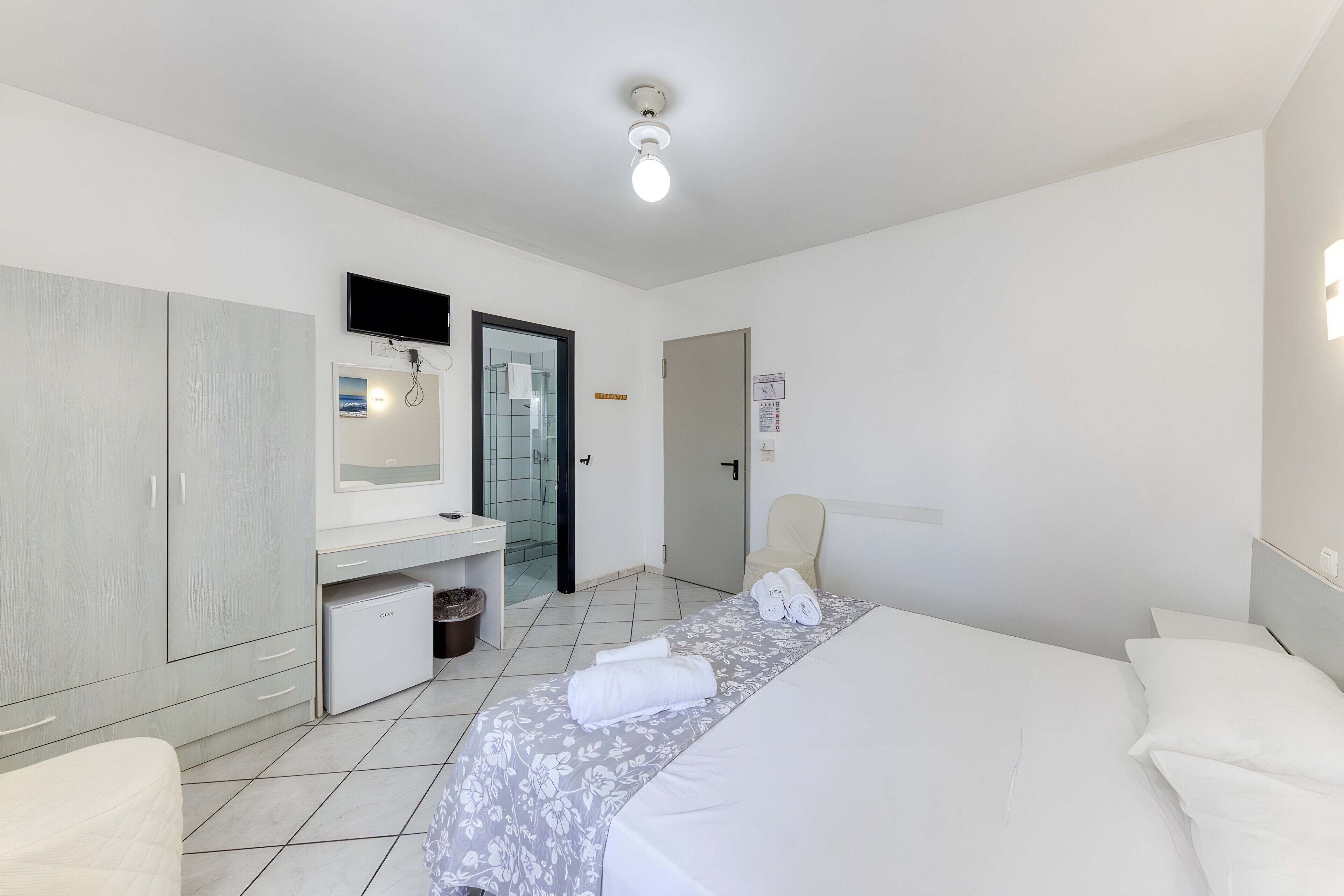 Une chambre d’hôtel comprenant un lit, un bureau, une chaise, une télévision et une salle de bain.