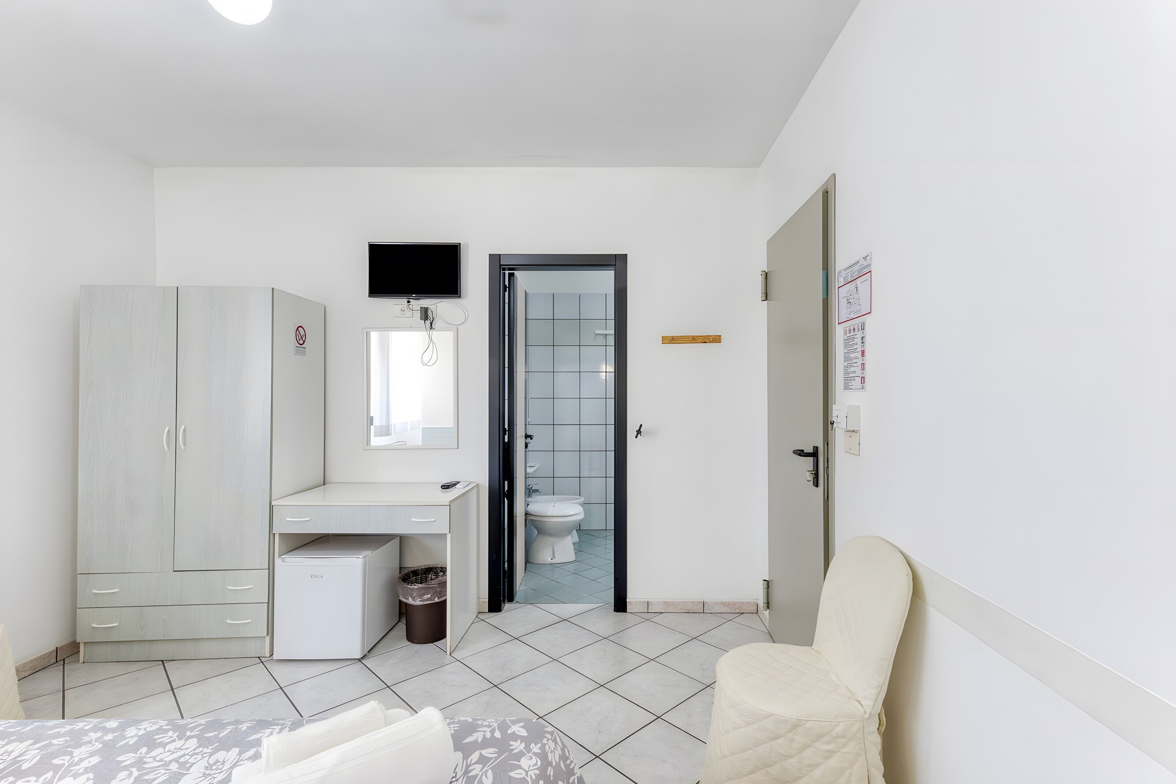 Ein Schlafzimmer mit Bett, Schreibtisch, Kleiderschrank, Toilette und Stuhl.