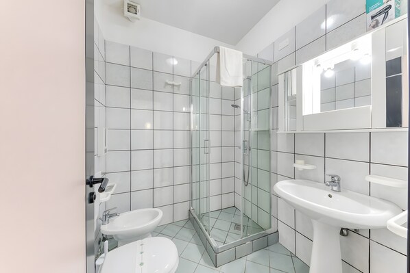 A bathroom with a glass-enclosed shower, two sinks, and a mirror. - Inn 'Doppia 3' with Balcony, Wi-Fi and Air Conditioning (Torre San Giovanni Ugento)
