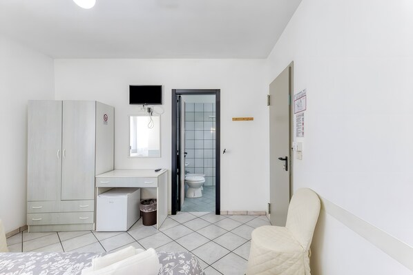Une chambre à coucher comprenant un lit, un bureau, une armoire, des toilettes et une chaise.