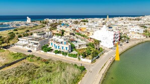 An aerial view of a coastal town with buildings, a marina, and a prominent tower. - Inn 'Quadrupla 1' with Wi-Fi and Air Conditioning (Torre San Giovanni Ugento)