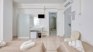 Une chambre d’hôtel avec deux lits, un bureau, une chaise, une télévision et un espace douche.