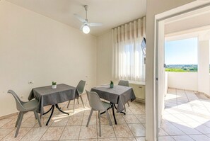 A dining area with two tables, chairs, a ceiling fan, and a view through a window. - Inn 'Tripla 2' with Wi-Fi and Air Conditioning (Torre San Giovanni Ugento)
