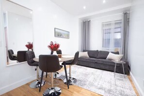A modern living room with a grey sofa, black chairs, a dining table, and a large mirror. - 3BR w/dishwasher, WD, elevator near Central Park W (New York)