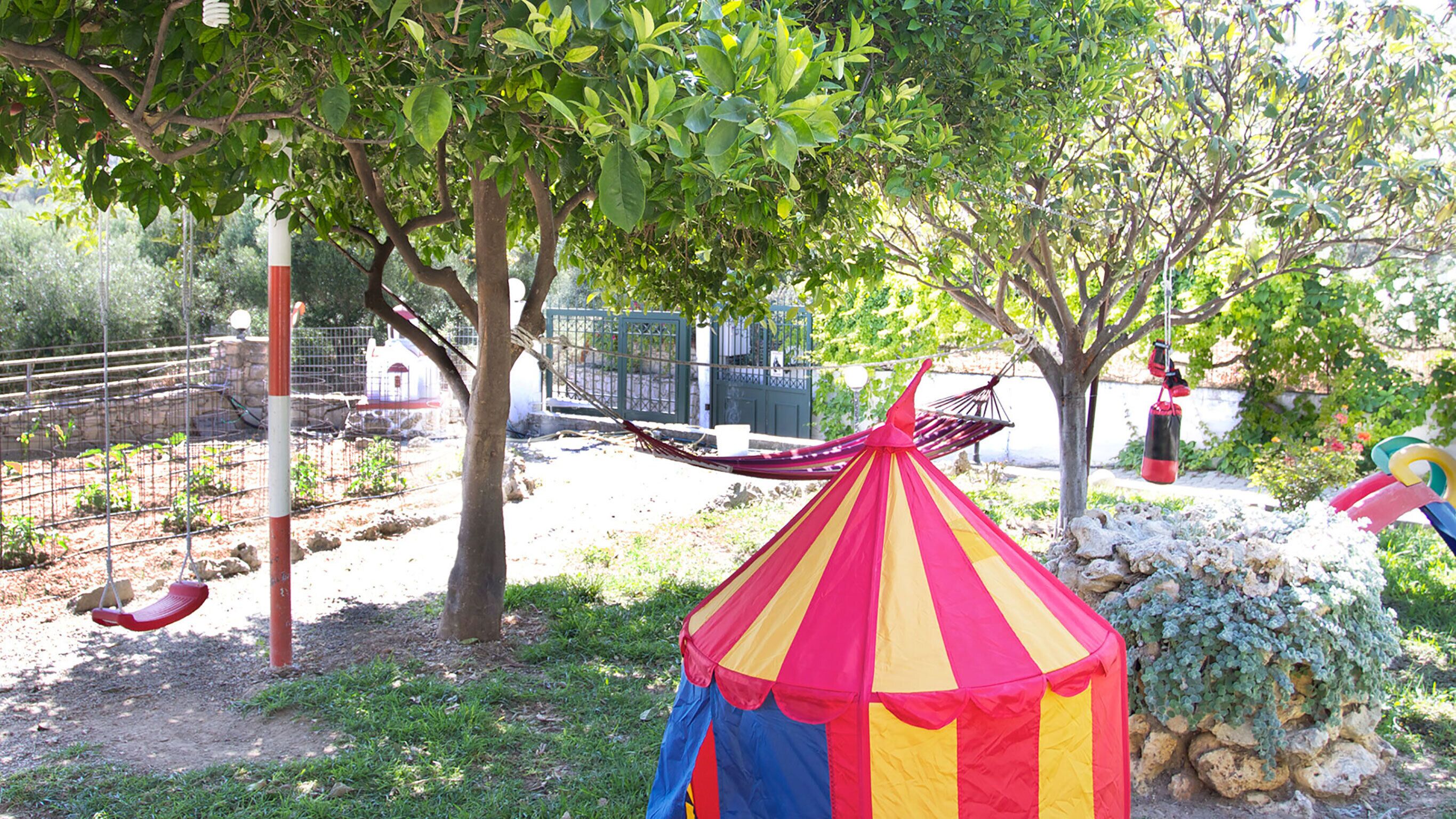 Een speeltuin met een schommel, een hangmat en een kleurrijke tent.