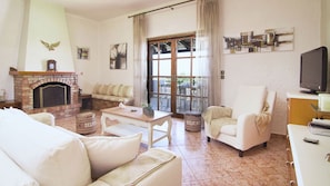 A living room with a fireplace, a sofa, a coffee table, and a television. - Villa Aetos (Rethymno)