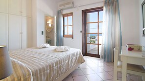 A bedroom with a bed, a bathroom, a desk, and a view of the outdoors. - Villa Aetos (Rethymno)