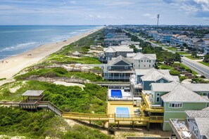 A coastal residential area with houses, a beach, and a boardwalk. - Nags Head Oceanfront w/ Pool, Sauna, Hot Tub! (Nags Head)