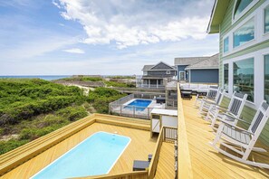 A deck with a pool, outdoor seating, and a view of the beach. - Nags Head Oceanfront w/ Pool, Sauna, Hot Tub! (Nags Head)