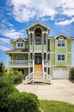 A two-story house with a front porch, a garage, and a driveway. - Nags Head Oceanfront w/ Pool, Sauna, Hot Tub! (Nags Head)
