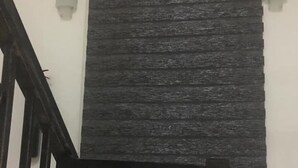A staircase with a metal railing and a window with a textured blind. - Hotel Guidotti (Abuja)