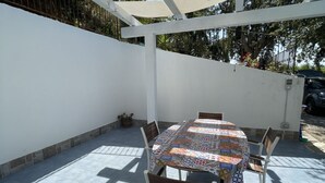 A covered patio with a round table and chairs, a tiled floor, and a white wall. - Villa Alice is an independent newly built villa, designed in the traditional “dammuso” style with its characteristic dome and overlooking the sea. It is a retreat immersed in nature, perfect for those seeking peace, privacy and an authentic stay. The (Marina di Caronia)