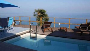 An outdoor swimming pool with lounge chairs and a wooden deck. - Villa Alice is an independent newly built villa, designed in the traditional “dammuso” style with its characteristic dome and overlooking the sea. It is a retreat immersed in nature, perfect for those seeking peace, privacy and an authentic stay. The (Marina di Caronia)