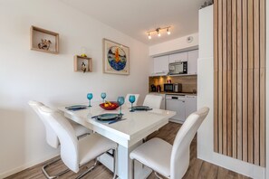 A modern kitchen with white cabinets, a microwave, and a dishwasher. - Cap Lanroz - Avec terrasse (Brest)