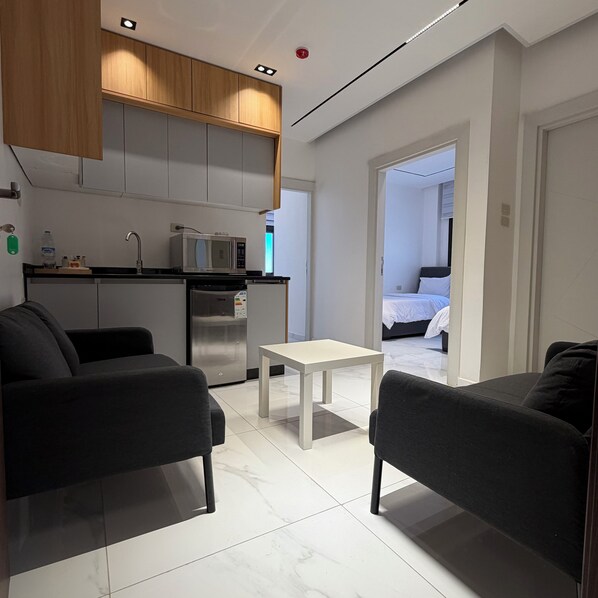A modern hotel room with a kitchenette, a dining area, and a bedroom. - Riva suites (Irbid)