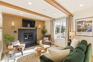 A modern living room with a fireplace, seating area, and a large window with a view. - Walk to Ski, 2 Kings, Luxury Park City Condo (Park City)