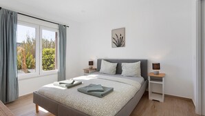 Un dormitorio moderno con una cama grande, dos mesitas de noche y un ventanal con cortinas.
