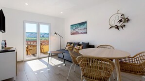 Et moderne interiør med spiseplads, sofa og udsigt gennem glasdøre.