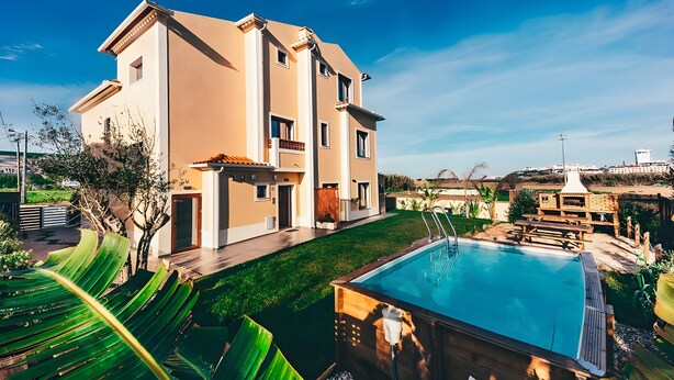 Et toetagers hus med swimmingpool, terrasse med udendørs møbler og en velplejet græsplæne.