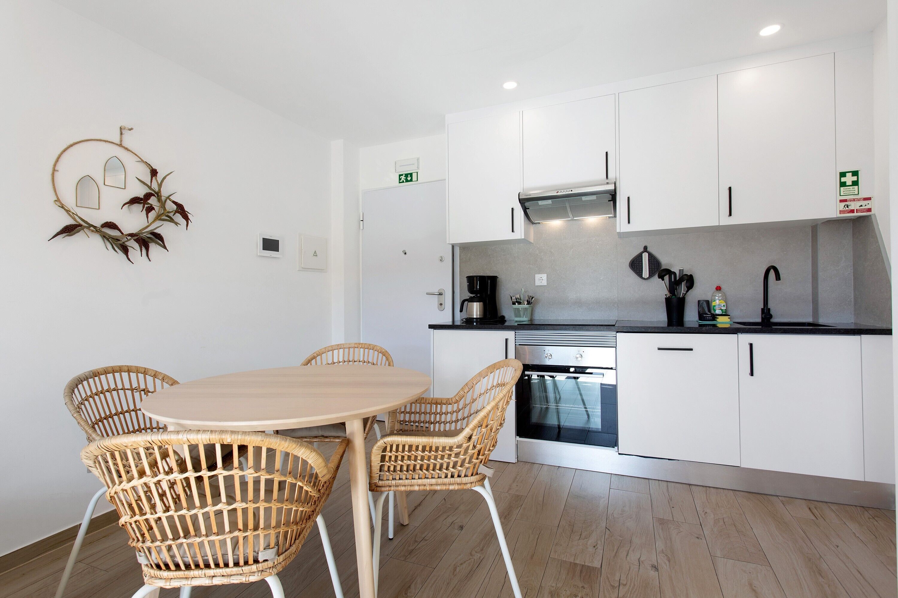 Una cocina moderna con armarios blancos, una mesa redonda y sillas de mimbre.