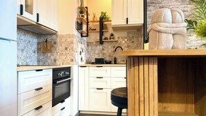 Een moderne keuken met witte kasten, een houten aanrecht, een inbouwoven en een stenen sculptuur.