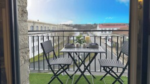 Een balkon met een tafel, stoelen, een kaars en uitzicht op gebouwen.