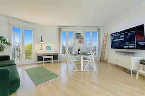 Ein modernes Apartment mit Essbereich, Fernseher und Balkon.