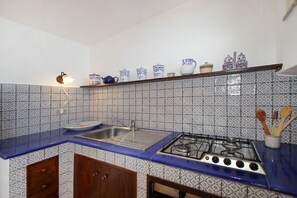 Eine Küche mit blauer Arbeitsplatte, einem Gasherd, einer Spüle und gefliestem Rücksprung mit Muster.