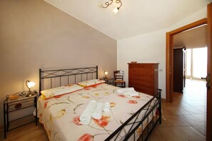 Ein Schlafzimmer mit einem Bett, Nachttischen, einem Schminktisch und einem Sessel.