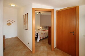 A bedroom with a bed, a wooden door, and a small hallway. - La Terrazza sul Mare is an elegant top-floor apartment designed for those who want to experience the authentic atmosphere of Sicilian seaside villages, surrounded by ceramics, sea views, and tranquility.Inside, you will find a bright living room with a f (Santo Stefano di Camastra)