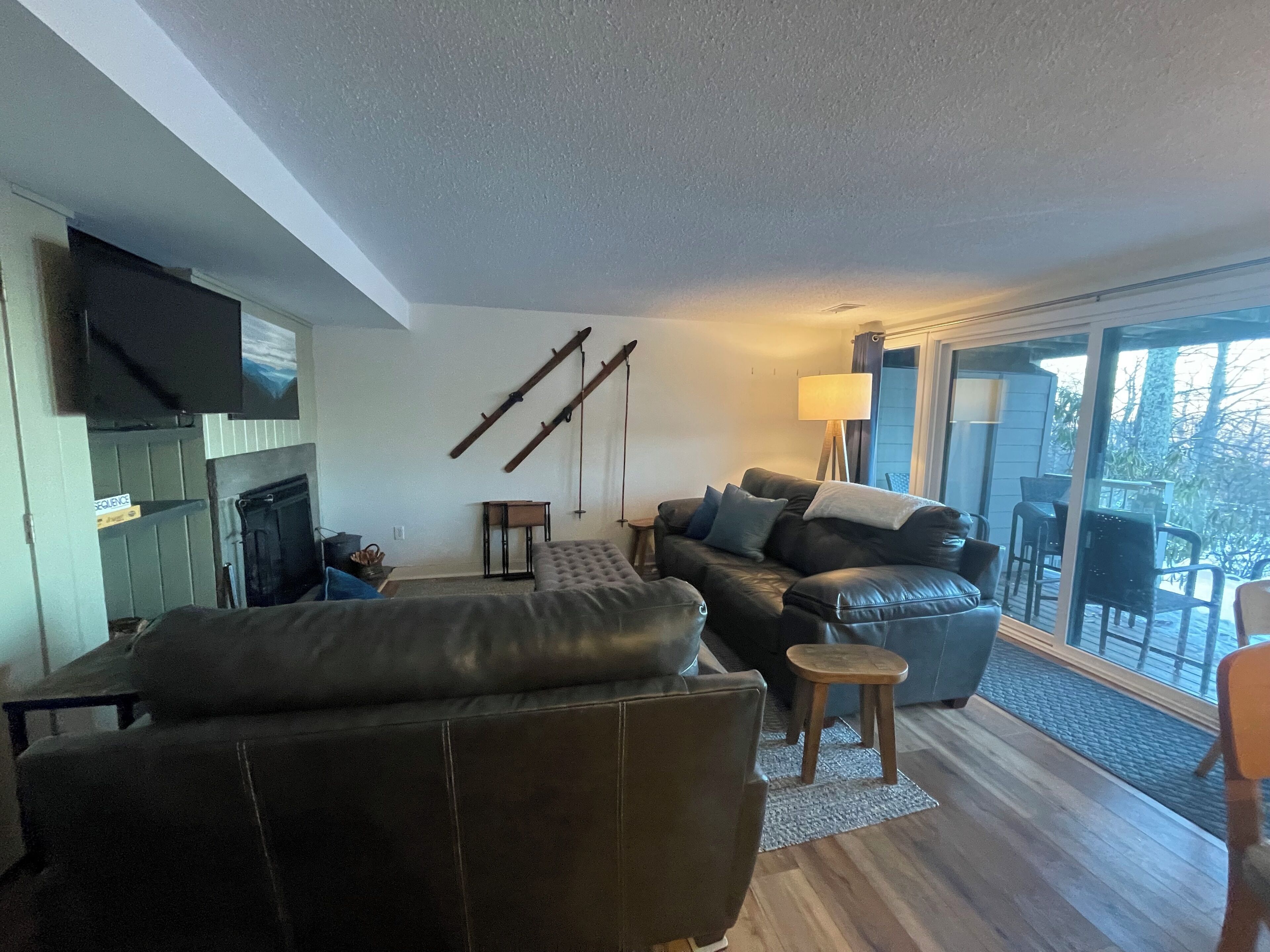 A modern living room with a leather sofa, a small table, and a TV mounted on the wall.