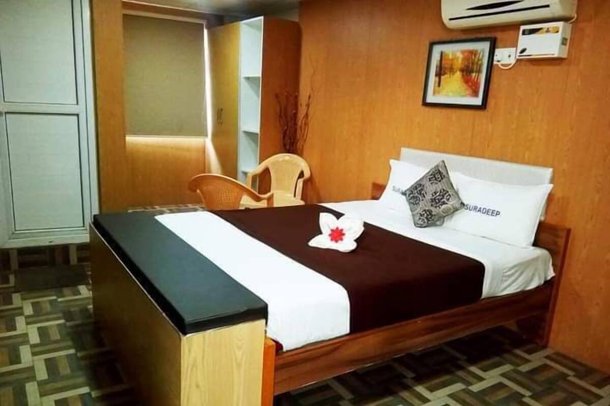 Una habitación de hotel con cama, escritorio, silla y aire acondicionado.