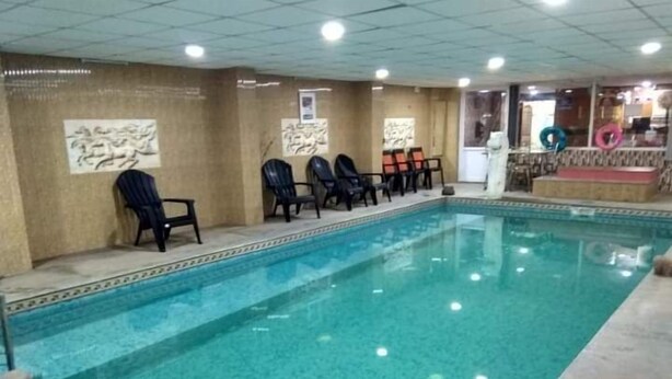 Una piscina interna con acqua limpida, circondata da sedie a sdraio e un pavimento piastrellato.