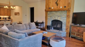 A living room with a stone fireplace, a television, and a sofa. - Snowcreek Resort Vacation Rental 1513 (Mammoth Lakes)