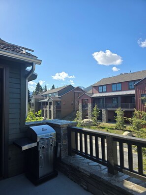 A residential area with a barbecue grill, stone pathway, and houses with balconies. - Snowcreek Resort Vacation Rental 1513 (Mammoth Lakes)