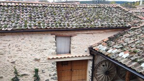 A rustic building with a stone facade, a wooden door, a small window, and a traditional cart. - Cottage next to a river in a quiet village, ideal for families. (Castroserna de Arriba)