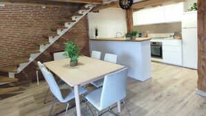 A modern kitchen with white cabinets, a wooden island, and a brick wall. - Cottage next to a river in a quiet village, ideal for families. (Castroserna de Arriba)
