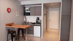 Una cucina moderna con un tavolo di legno, due sgabelli da bar, un forno a microonde, un tostapane e un frigorifero.