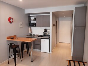 Une cuisine moderne avec une table en bois, deux tabourets de bar, un four à micro-ondes, un grille-pain et un réfrigérateur.