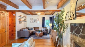 Een gezellige woonkamer met een open haard, houten balken en een stenen muur.