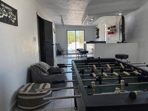 Une pièce avec une table de baby-foot, un canapé et un panneau accroché au mur.