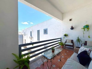 A balcony with a glass table, a sofa, and potted plants. - Casa grande céntrica 19 huéspedes wifi 500Mbps (Matamoros)
